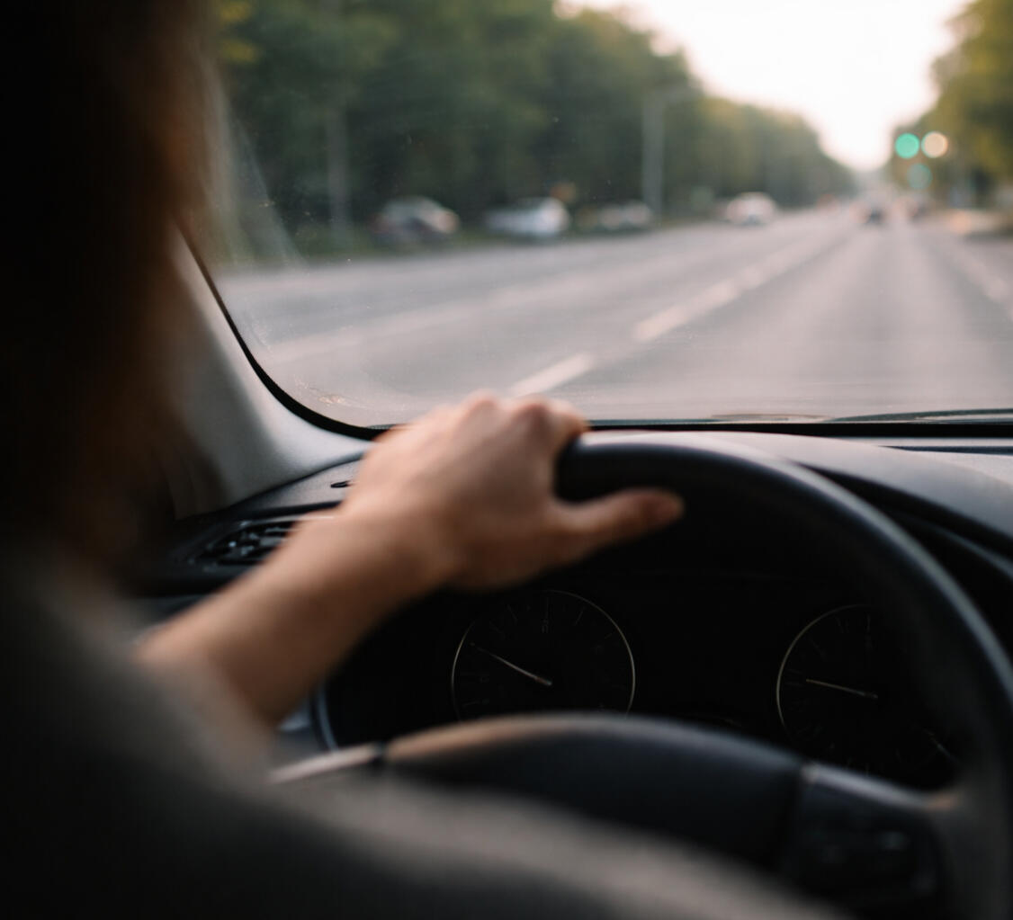 Driver holding the steering wheel while looking down the road symbolizing a leader deciding the next direction